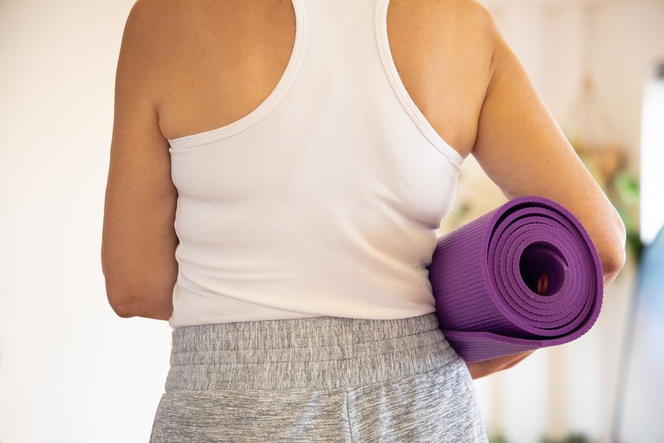 Perempuan bersiap olahraga di rumah dengan yoga mat